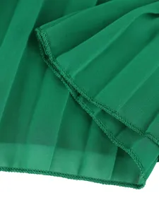 Detailed macro shot of the green pleated fabric and hem stitching on wide-leg trousers