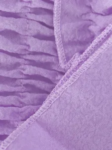 Primer plano macro de tela fruncida púrpura que muestra la textura suave y la costura