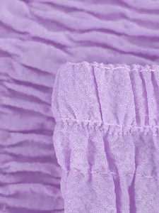 Vista detallada de la textura de la tela fruncida púrpura y las costuras en la prenda