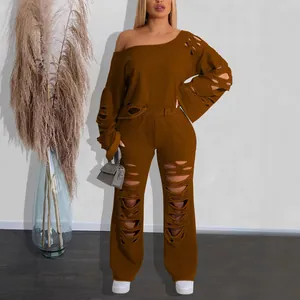 Stylish brown two-piece set featuring off-the-shoulder ripped sweatshirt and cutout pants.