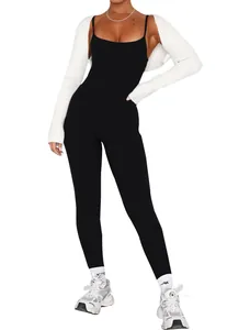 Detailed view of backless black jumpsuit styled with white ribbed shrug and sneakers