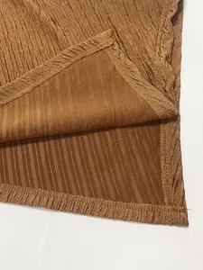 Primo piano del tessuto plissettato caramello con trama a coste e cuciture pulite.