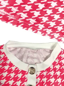 Detailaufnahme eines pinkfarbenen Hahnentritt-Musters mit elegantem goldenem Löwenknopf