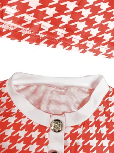 Nahaufnahme eines rot-weißen Houndstooth-Oberteils mit dekorativem goldenem Löwenknopf.