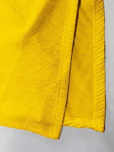 Primo piano del tessuto strutturato giallo brillante con spacco laterale