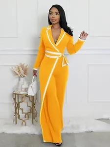 Elegante mono amarillo de manga larga con ribetes blancos en contraste y lazo en la cintura.