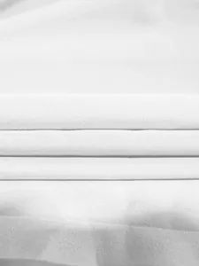 Gros plan sur un tissu plissé blanc montrant une texture fine et un travail élégant.