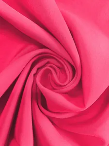 Gros plan détaillé de la texture d'un tissu de robe plissé rose vif avec drapé souple