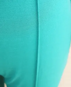 Close-up detail of turquoise fabric texture and seam on a commuter jumpsuit