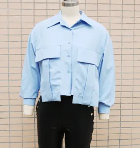 Detail of light blue loose-fit blouse with unique pleated pocket design