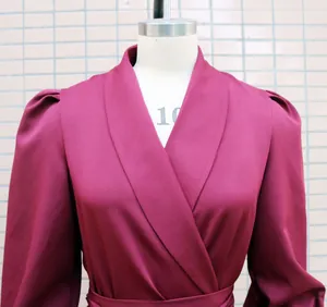 Macro view of the burgundy shawl collar and pleated sleeve details on a women's dress