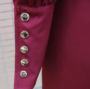 Close-up of wine red dress sleeve with five silver metallic dome buttons