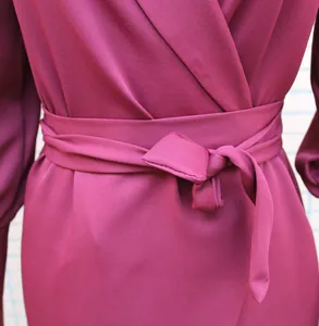 Detailed view of the elegant tied waist sash and fabric texture on a maroon wrap dress