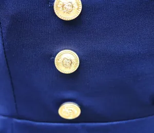 Nahaufnahme von dekorativen goldenen Wappenknöpfen auf einem eleganten dunkelblauen Midikleid