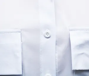 Macro detail of a white office shirt showing the button and fine stitching on pockets