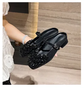 Close-up of black Mary Jane block heel mules with rhinestone embellishment on the toe.