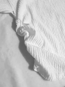 Macro view of white crinkled and textured fabric for the elegant vacation outfit set.