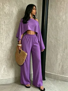 Vista detallada de conjunto morado de dos piezas con top asimétrico y pantalón ancho