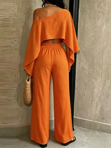 Detalle de conjunto naranja con top asimétrico y pantalón ancho para vacaciones en la playa