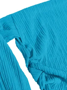 Close-up detail of blue crinkled fabric texture and knot design on vacation top.