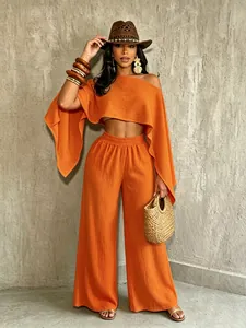 Detalle del conjunto de vacaciones naranja con top asimétrico y pantalones de pernera ancha.