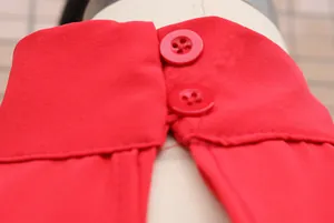 Close-up macro detail of a red mock neck sleeveless romper featuring two buttons