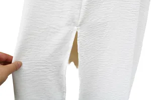Detalle de la tela con textura blanca y abertura lateral en un vestido midi de playa