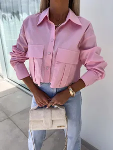 Detailed view of women's loose pink long-sleeve blouse with batwing sleeves and pockets