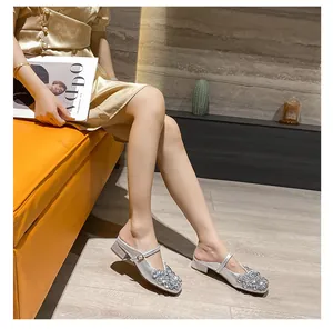 Side view of silver rhinestone Mary Jane block heel mules worn by model in elegant room