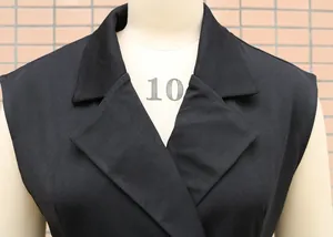Detail view of a black sleeveless dress showing the sophisticated notched lapel design
