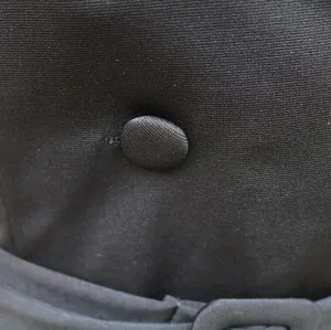 Close-up macro view of a fabric-covered button on a black commuter office dress garment