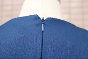 Detailaufnahme eines dunkelblauen Overalls mit verdecktem Reißverschluss hinten.