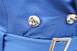 Makrodetail eines blauen Jumpsuit-Stoffs mit Metallknöpfen und einem Schnallenverschluss.