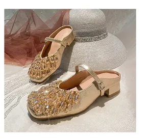 Detailed view of gold Mary Jane block heel mules with sparkling rhinestone toe embellishment