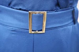 Nahaufnahme der eleganten goldenen Schnalle am blauen Stoffgürtel eines Damen-Overalls