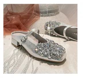 Close-up of silver square toe Mary Jane mules with glittering rhinestone embellishments.