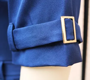 Nahaufnahme des Ärmelriemens und der goldfarbenen Metallschnalle des blauen Overalls
