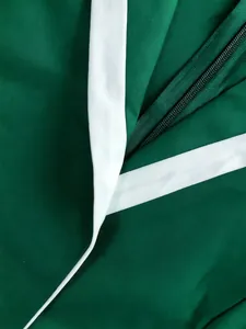 Detalle macro de un mono de moda verde esmeralda con ribetes blancos y cremallera oculta