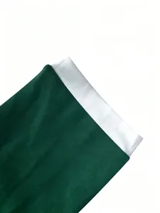 Detalle de primer plano de la manga de patchwork bicolor verde esmeralda y blanco en el mono