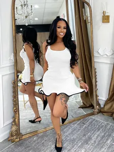 Sleeveless ribbed white mini dress with black ruffled hem shown on a model in a mirror.