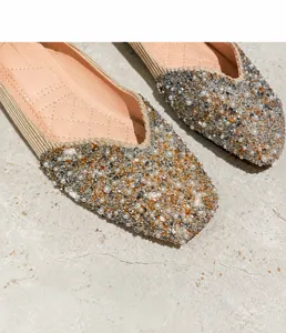 Dettaglio ravvicinato di paillettes e perle su scarpe basse da donna con punta quadrata