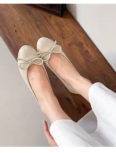 Close-up detail of beige patent leather ballet flats with elegant bow and round toe