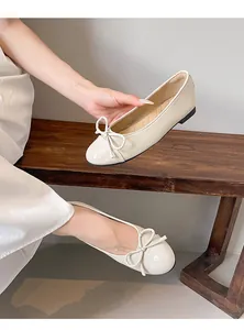 Detailed macro view of French style cream ballet flats with elegant bow and round toe