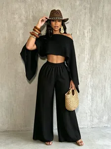 Vista completa de un conjunto negro de top corto con hombros descubiertos y pantalones anchos.