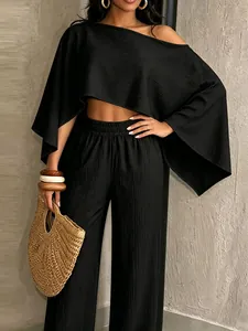 Detalle de conjunto negro de dos piezas con top asimétrico y pantalón ancho texturizado.