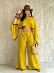 Detalle del conjunto de top asimétrico amarillo y pantalones anchos para vacaciones