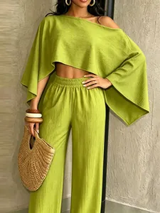 Primer plano de conjunto plisado verde lima con top asimétrico y pantalones anchos