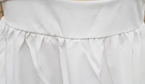 Detailaufnahme der Taillenfalten und Nähte eines weißen Maxikleids für Damen.