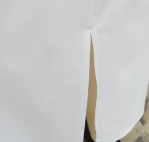 Detailaufnahme der sauberen Nähte und des Seitenschlitzes eines weißen Etuikleides.