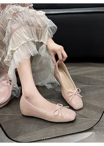 Detail view of pink leather ballet flats featuring a delicate bow and square toe design.
